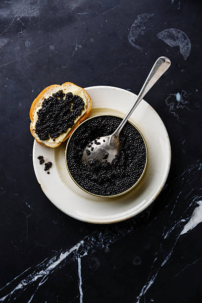 Sturgeon black caviar in can and sandwich Sturgeon black caviar in can and sandwich on black marble background roe stock pictures, royalty-free photos & images