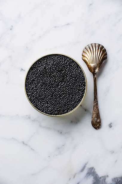 Sturgeon black caviar in can and spoon Sturgeon black caviar in can and spoon on white marble background roe stock pictures, royalty-free photos & images