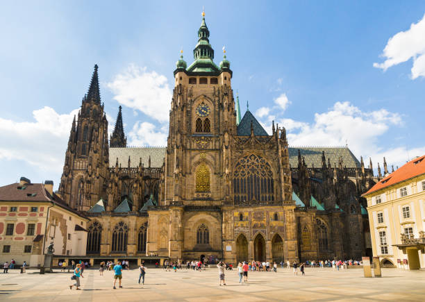 St.Vitus's Cathedral on Hradčany Square in Prague, Czech Republic Prague, Czech Republic May 25th. 2018: Tourists and locals are walking on Hradčany Castle Square. Royal Castle is on the right and St.Vitus's Cathedral is in the center of the photograph. This photograph was taken in the afternoon with full frame camera and Zeiss wide-angle lens. hradcany castle stock pictures, royalty-free photos & images