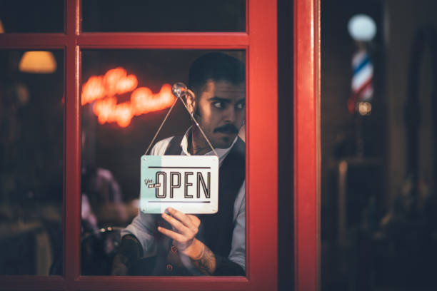 Stylish barber opening barber shop with sign on business door Barber with mustache opening vintage barber shop standing at small business window with open signboard vintage beauty salon stock pictures, royalty-free photos & images