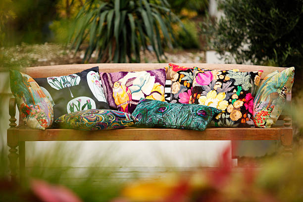 Stylish cushions on wooden seat placed in garden stock photo