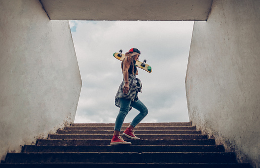 Stylish girl with a skateboard on the stairs