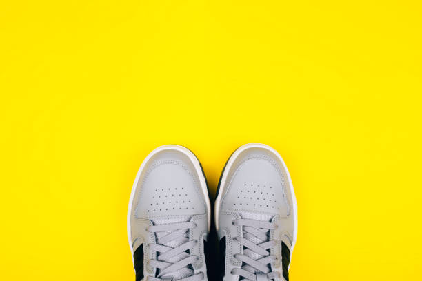 eleganti sneakers grigie su sfondo giallo. - shoes top view foto e immagini stock