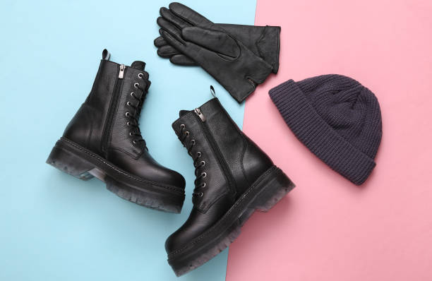 Stylish leather boots, beanie hat and gloves on blue pink pastel background stock photo