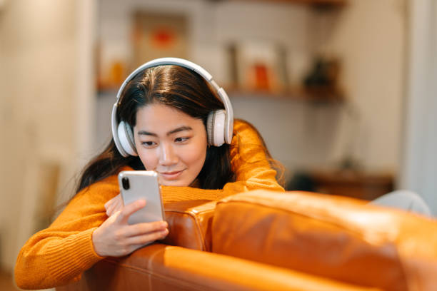 自宅で音楽を聴くスタイリッシュな若い女性 - スマホ　女性　日本人 ストックフォトと画像