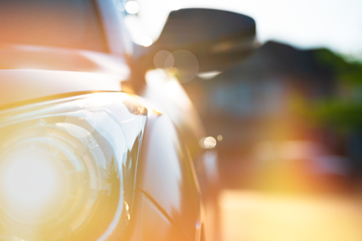 Highly Stylizes depiction of a generic vehicle in golden light of summertime - close up of front headlight and side mirror.