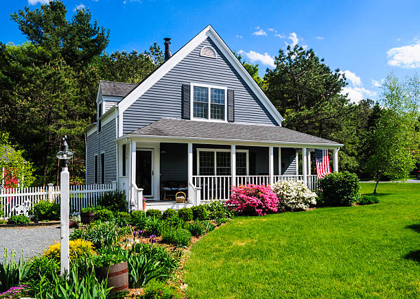 Suburban Spring An American flag flies from the open porch and gardens surround a small  single family home on a Spring afternoon on Cape Cod on the Massachusetts coast. (Property release attached) new england usa stock pictures, royalty-free photos & images