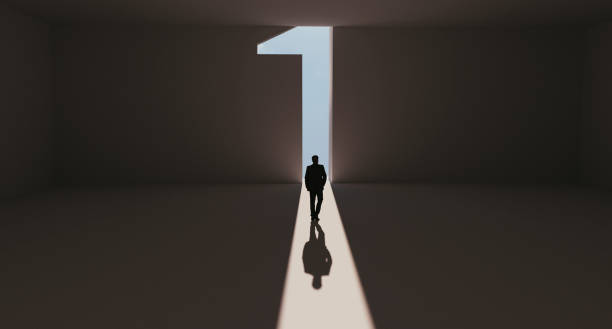 Success for man who reaches first place and stands out from the crowd Man walks towards a big number one symbol that lights up. He is surrounded by darkness, but walks on a path of sunshine reaching first place. Note: Digitally generated image. number 1 stock pictures, royalty-free photos & images