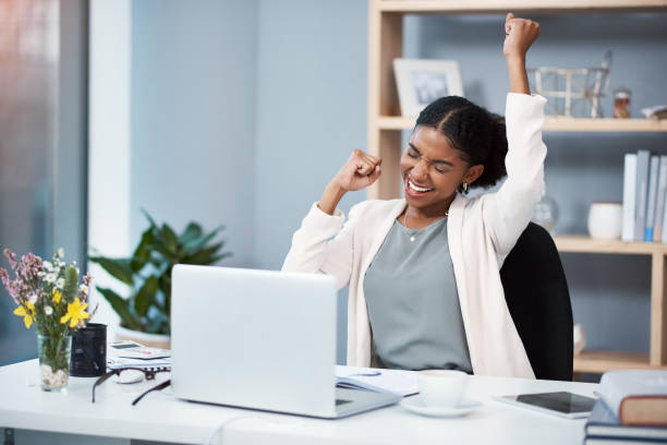 Success happens when you combine passion with ambition Shot of a happy young businesswoman celebrating at her desk in a modern office incentive photos stock pictures, royalty-free photos & images