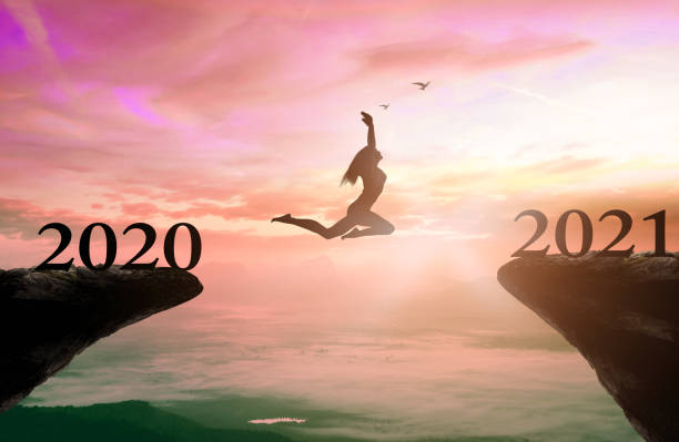 Success new year 2021 concept Silhouette woman jump between 2020 and 2021 years with sunset background new years eve girl stock pictures, royalty-free photos & images