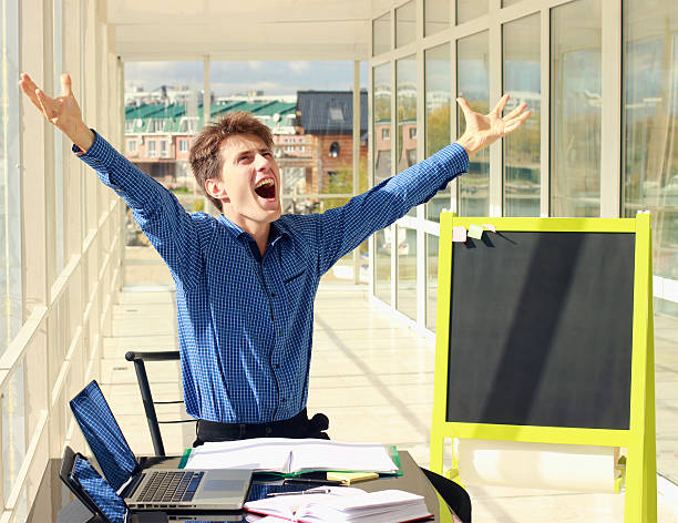 Successful businessman raising arms at workplace. stock photo