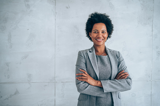 Portrait of beautiful confident smiling african-american businesswoman standing with arms crossed in the office and looking at camera.