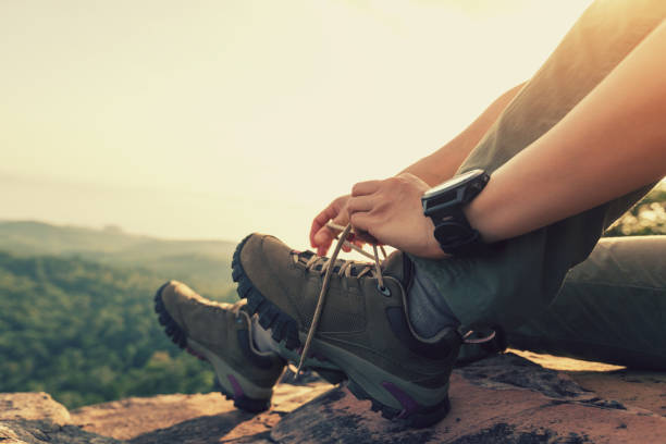 Successful hiker sit and tying shoelace on mountain peak cliff edge stock photo