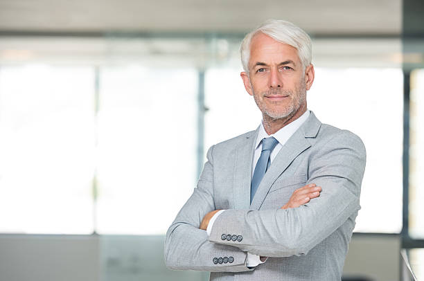 Successful leadership Portrait of a senior businessman with arms crossed in his modern office. Successful business man with arms folded looking at the camera. Portrait of a happy senior businessman in formal smiling. cfo stock pictures, royalty-free photos & images