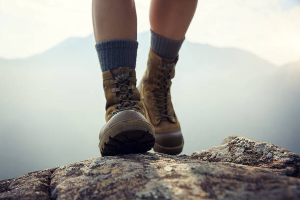 Suceesful woman hiker legs stand on mountain peak cliff edge stock photo