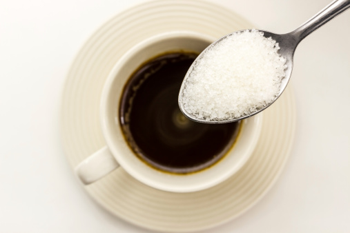 Sugar in the spoon pour into coffee cup.