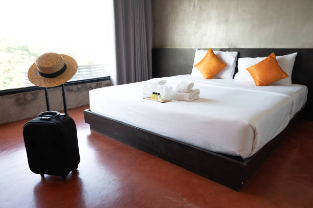 A suitcase with hat in comfortable hotel bedroom in cozy style. stock photo