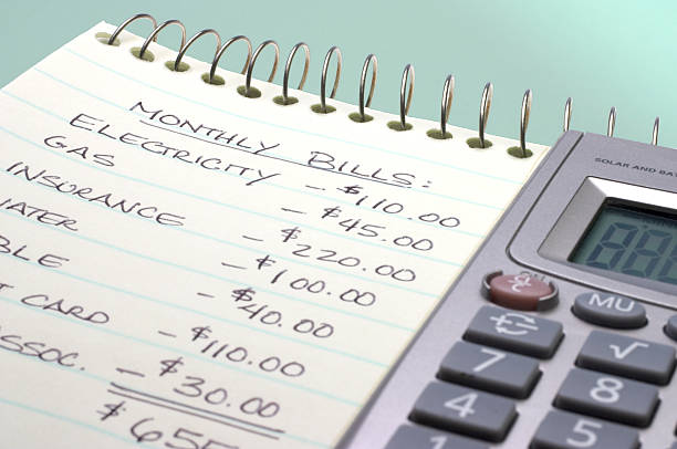 Summation of monthly bills on a notepad by a calculator stock photo