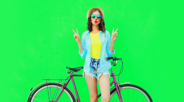 Summer colorful image of happy young woman with bicycle on vivid green background stock photo