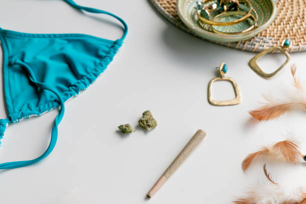 Summer Festival Essentials Blue Bikini and Gold on Light Blue with Pre-roll, Marijuana buds, Turquoise, Gold, feathers, and Bikini stock photo