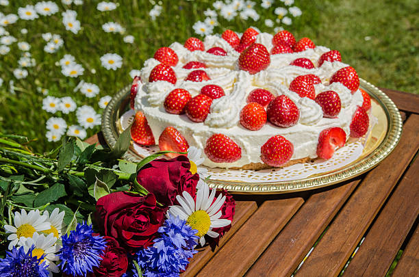 Summer flowers at a table with a homemade strawberry cake stock photo