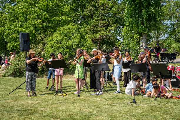Summer garden front view of adults and young people in an orchestra with instruments playig classical music together. stock photo