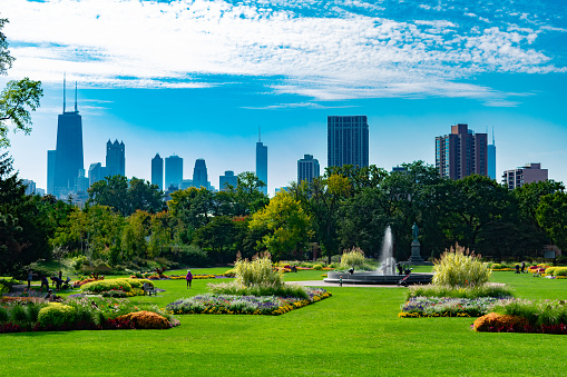 A large garden scene with plants and a fountain in Lincoln Park Chicago with the city skyline