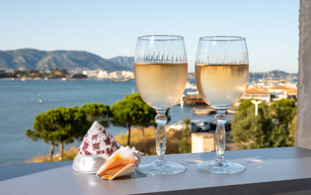 Summer on French Riviera, drinking of cold white or gris rose wine from Cotes de Provence on outdoor terrase with view on harbour of Toulon, Var, France and sea shells stock photo