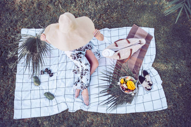 A summer picnic, a girl in a big beautiful beach hat , with a plate...
