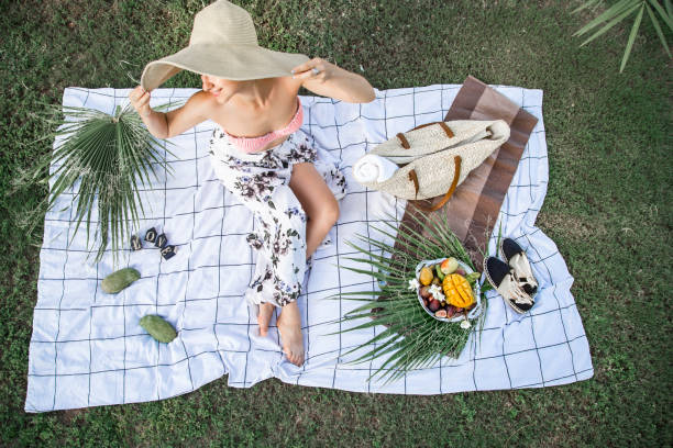 A summer picnic, a girl in a big beautiful beach hat , with a plate...
