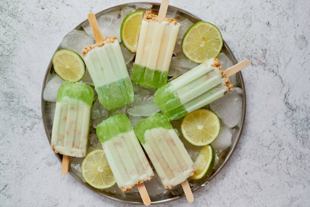 Summer refreshing homemade lime popsicles with chipped ice over stone background stock photo