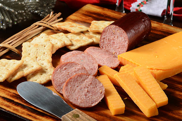 Summer sausage and cheese Sliced summer sausage with cheddar cheese and crackers on a holiday table sausage stock pictures, royalty-free photos & images