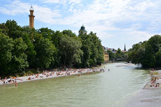 Summer Sunbathing at Isar beach, Munich Germany Isar beach in Munich. Locals and tourists spreading their towels for sunbathing on the gravel beach and refreshing in the cold river water on hot summer day.  river isar stock pictures, royalty-free photos & images