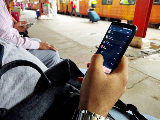 summer travel,hipster boy using smart phone mobile at platform of new delhi railway station - whatsapp stockfoto's en -beelden