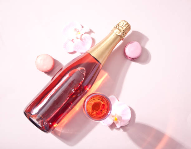 Summer tropical glass of pink cocktail wine champagne with bottle decorated pink orchid flowers and macaroons. Top view. Summer tropical glass of pink cocktail wine champagne with bottle decorated pink orchid flowers and macaroons. Top view happy birthday wine bottle stock pictures, royalty-free photos & images