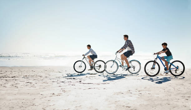 de zomers zijn voor het maken van deposito's in de familie-geheugenbank - fietsen strand stockfoto's en -beelden