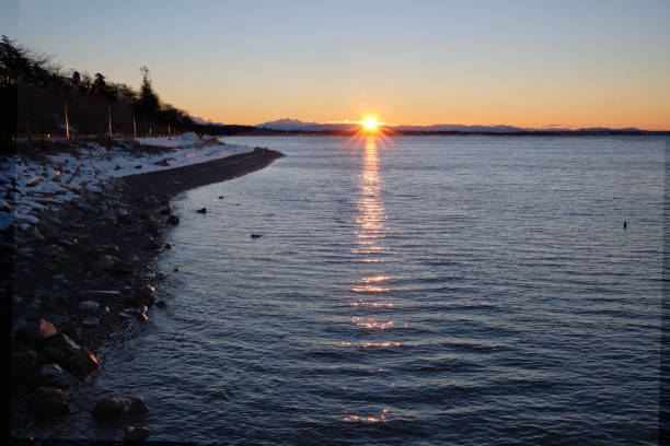 Sun bursts over North Cascades Mountains and Semiahmoo Bay stock photo