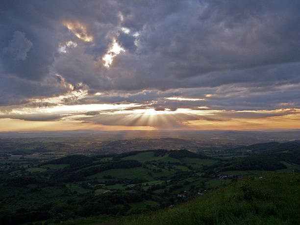 Sun Rays Up Malvern Taken up the Malvern Hills looking over to Wales this sunset was taken on a cloudy evening with the sun rays beaming through the clouds.  normalisaverage stock pictures, royalty-free photos & images