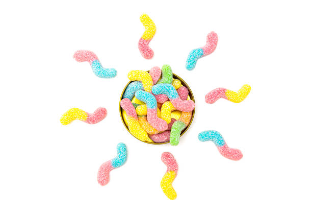 Sun shape made of vibrant gummy worms Creative flat lay made of colored sugar coated gummy worms sun shaped around a tin box isolated on white sour taste stock pictures, royalty-free photos & images