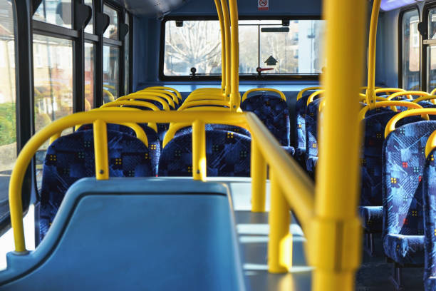Sun shines on empty interior of London double decker bus, yellow holding rails and blue seats stock photo