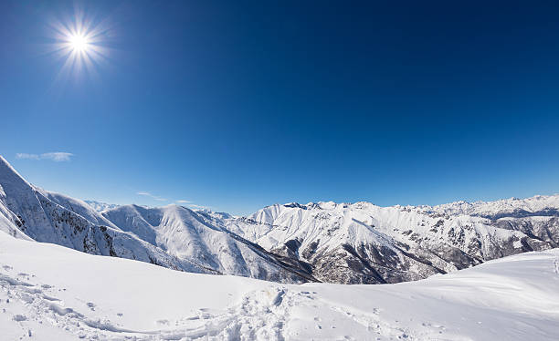Sun star glowing over snowcapped mountain range, italian Alps Sun star glowing over snowcapped mountain range and high mountain peaks in the italian alpine arc, in a bright sunny day of winter. Candid snowy slope in the foreground. himalayas stock pictures, royalty-free photos & images