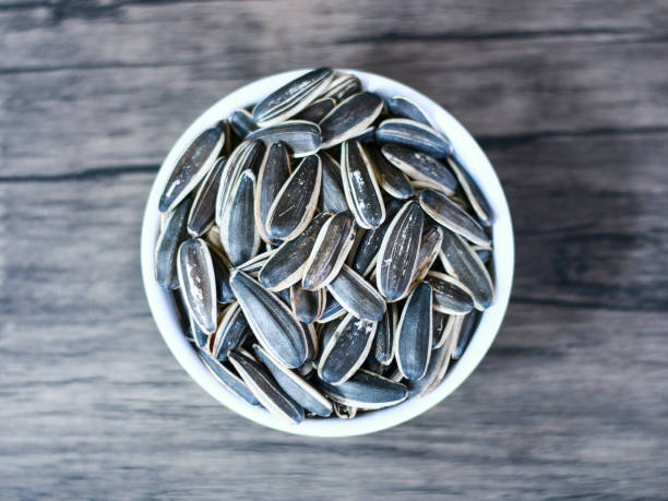 Sunflower seed snack Sunflower seed snack or kuaci on plate on wood background. kuaci stock pictures, royalty-free photos & images