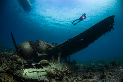 Image with a female diver, a boat and the navy floatplane, an Aichi E13A1-1 or Jake type reconnaissance seaplane. It's one of the most intact wrecks in Micronesia, resting at 45 feet (15m) in Koror, Palau - Micronesia