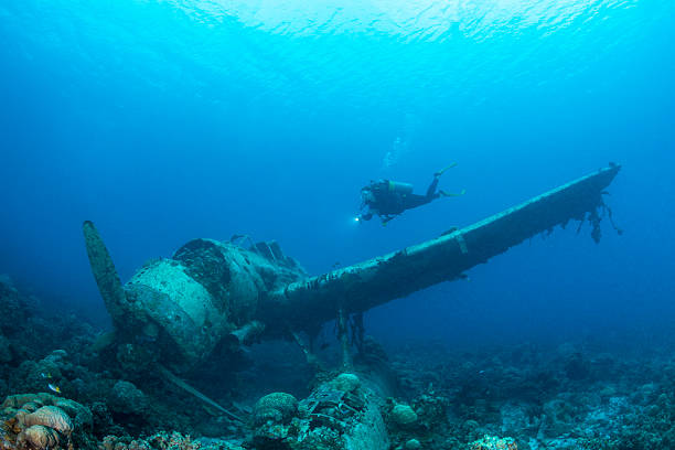 II WW Sunken Airplane Wreck -Palau This navy floatplane, an Aichi E13A1-1 or Jake type reconnaissance seaplane is one of the most intact wrecks in Micronesia, resting at 45 feet (15m). Beautiful scenario of a II WW Japanese seaplane sunken and a female scuba diver in Palau - Micronesia. The Jake could be found in many lagoons where the land mass did not support an airfield, but they also operated from cruisers and battleships. Two of the planes can be seen (in Palau) in very shallow waters in a cave of Babelthuap. babeldaob island stock pictures, royalty-free photos & images