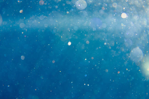 sunny blue underwater background with particles stock photo