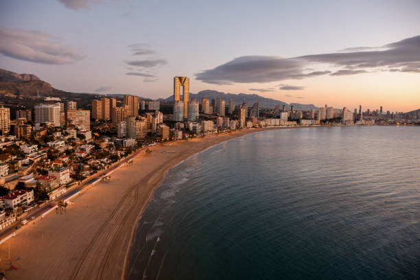 Sunrise in Benidorm with view on InTempo Building skyscrapers Benidorm skyline during a sunrise. Empty sandy beach with gentle waves of sea. Located in Costa Blanca, Spain in Alicante province. costa blanca stock pictures, royalty-free photos & images