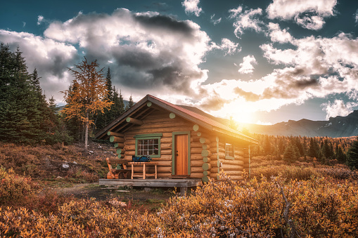 Alberta, Canada - Sep 22 2019 : Sunrise on wooden hut in autumn forest at Assiniboine provincial park, Canada