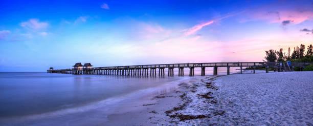 Sunrise over Naples Pier where people fish at dawn in Naples Sunrise over Naples Pier where people fish at dawn in Naples, Florida. naples florida beach stock pictures, royalty-free photos & images