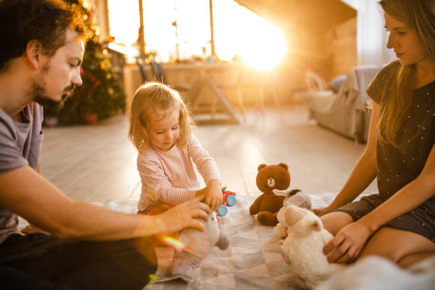 Sunrise play with mommy and daddy Cute girl playing on the floor with fur animals with her mom and dad teddy ray stock pictures, royalty-free photos & images