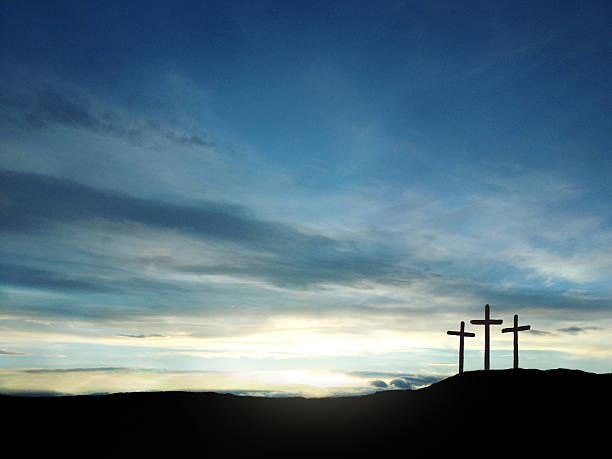 A depiction of the three crosses of Calvary with a beautiful sunrise or sunset with blue, yellow, purple and white colors.  The cross of Calvary is a spiritual symbol of the resurrection of Christ.